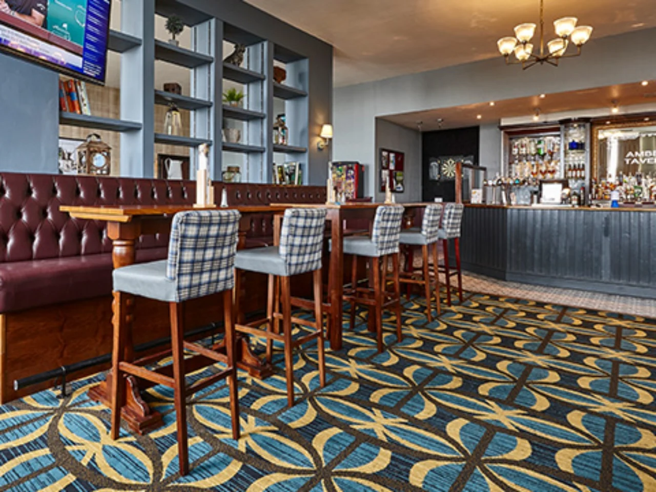 Patterned commercial carpet and upholstered bar seating in a pub interior